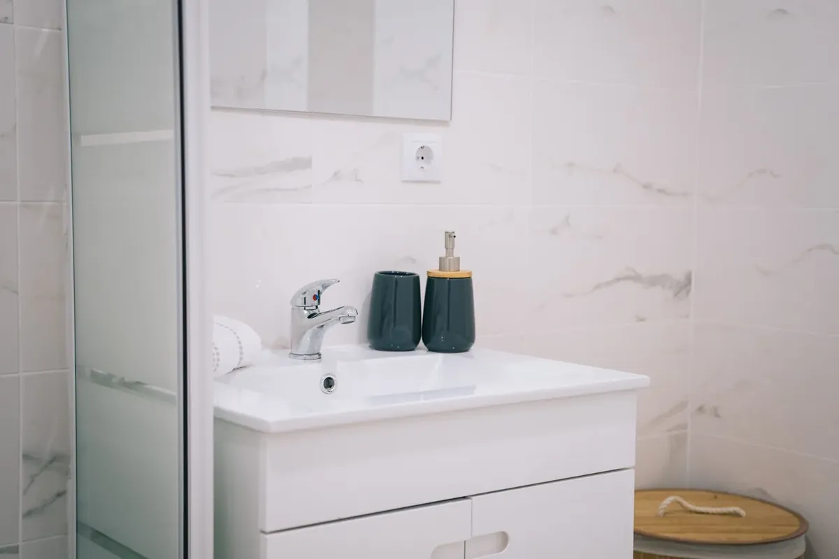 A white bathroom basin and chrome tap against pale tiled walls.
